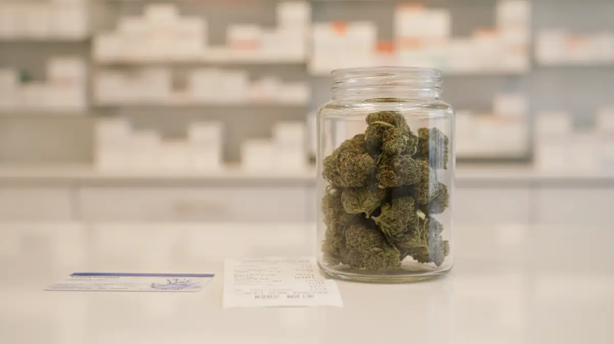 Pot de fleurs de cannabis médical posé sur un comptoir de pharmacie à côté d'une carte d'assurance maladie